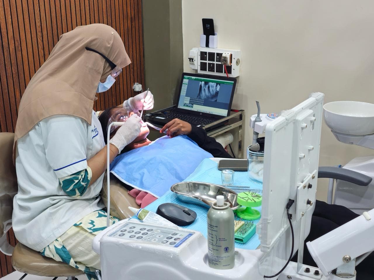 Dentist treating a patient beside the dental equipment