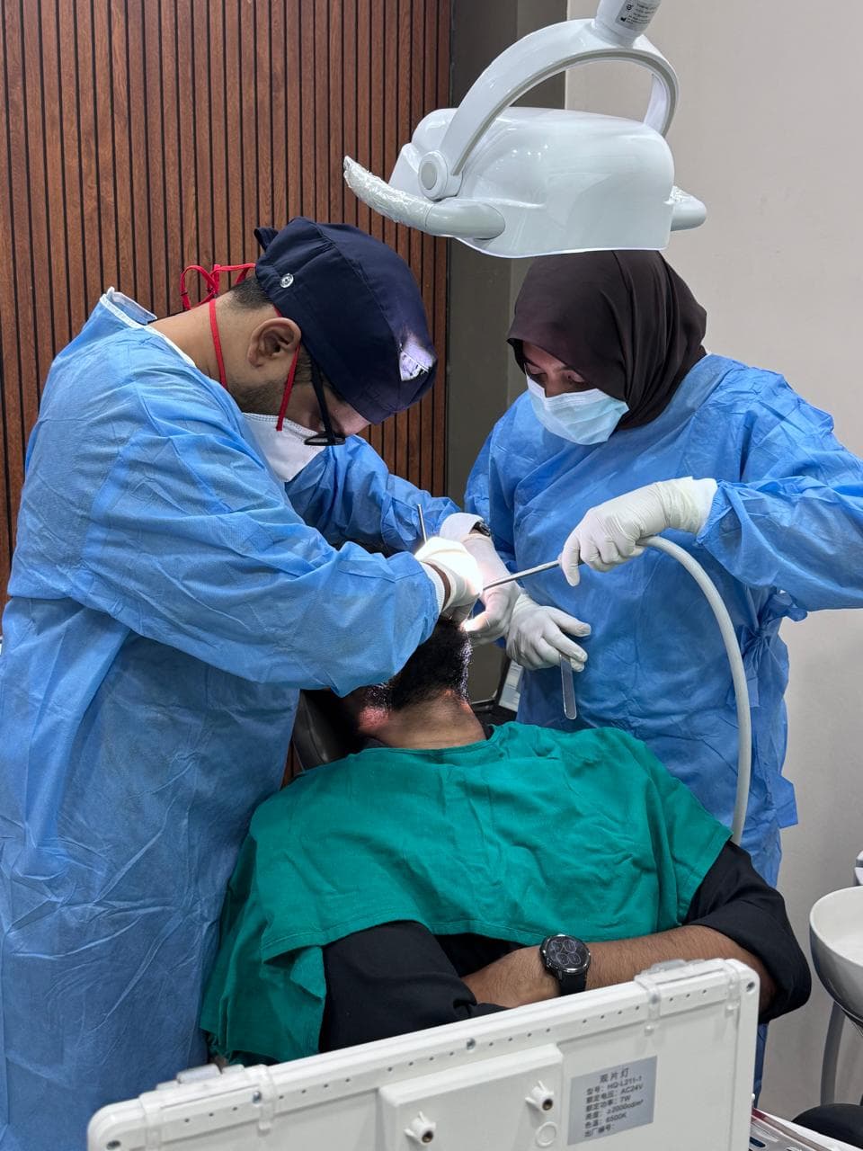 Two clinicians in blue gowns working together at META DENTAL